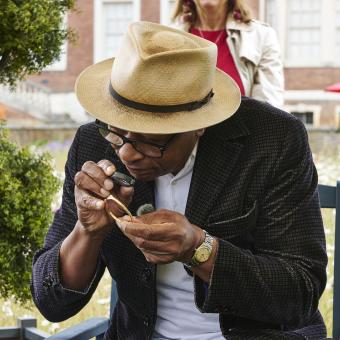 Ronnie Archer-Morgan examines an object at Ham House in London